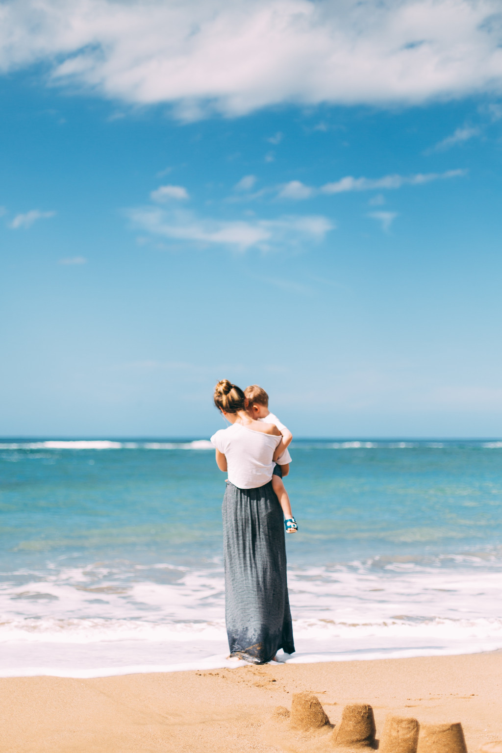 Mutter hält Kind auf dem Arm am Strand
